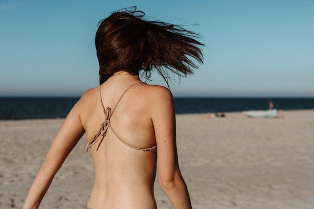 Back view of a woman in a brown bikini for the best collagen supplements to get summer-ready
